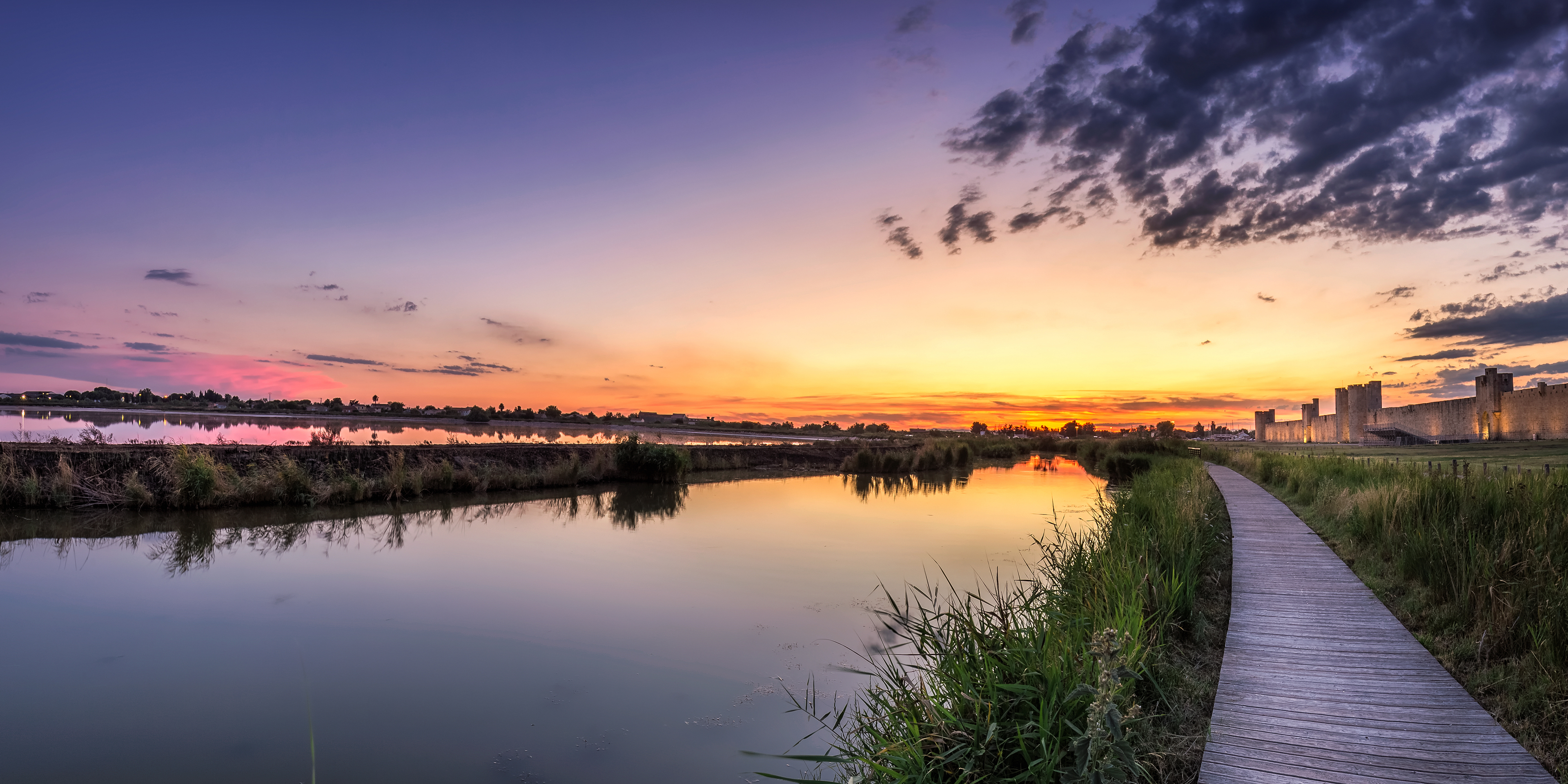 Canal de Camargue au coucher du soleil menant vers les remparts d'Aigues-Mortes