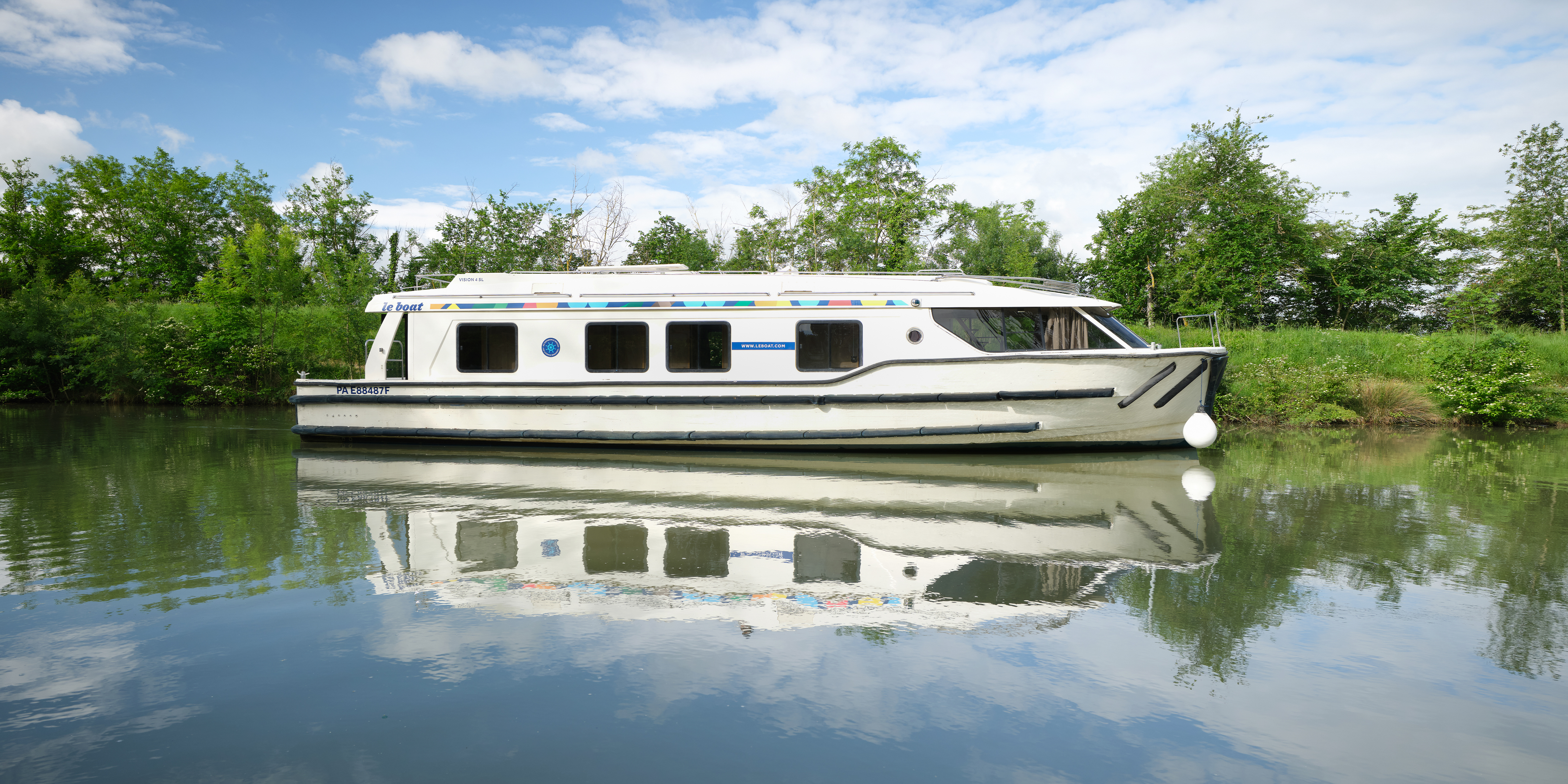 Vision 4 de Le Boat naviguant le long d'arbres verdoyants